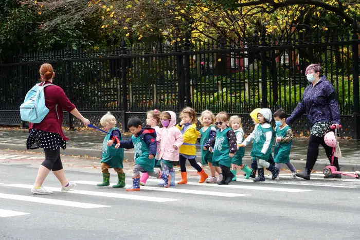 Preschool kids walk in a line on a New York City sidewalk.